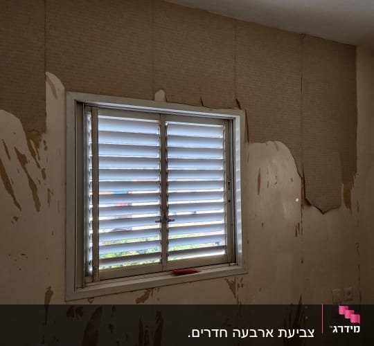 קיר עם טפט מתקלף ליד חלון